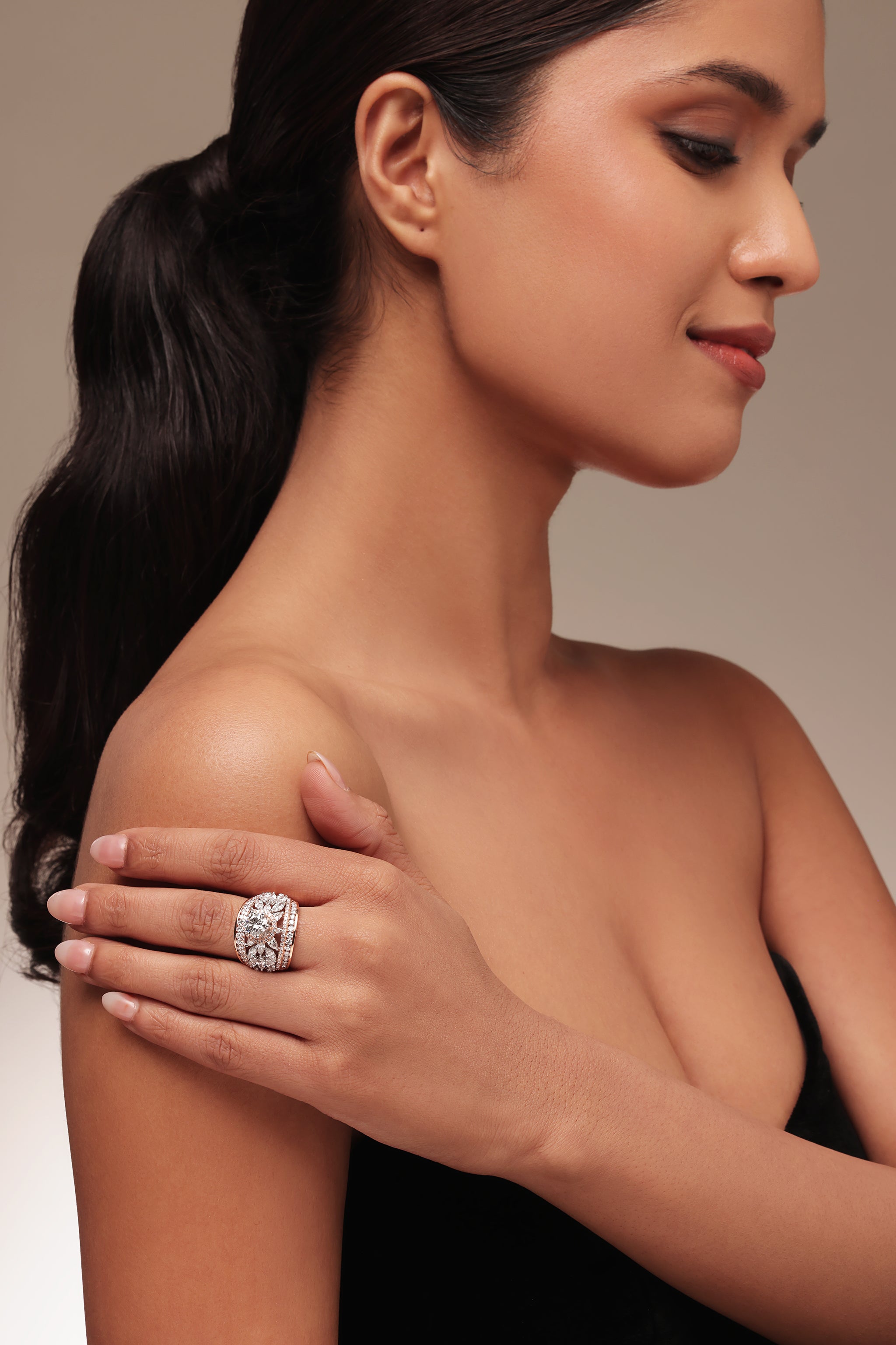 Close-up portrait of a woman modeling a dazzling cocktail ring with lab grown diamond in it. The intricate design features a prominent round solitaire with halo as the center, surrounded by elegant pear and marquise shaped diamonds on the sides.