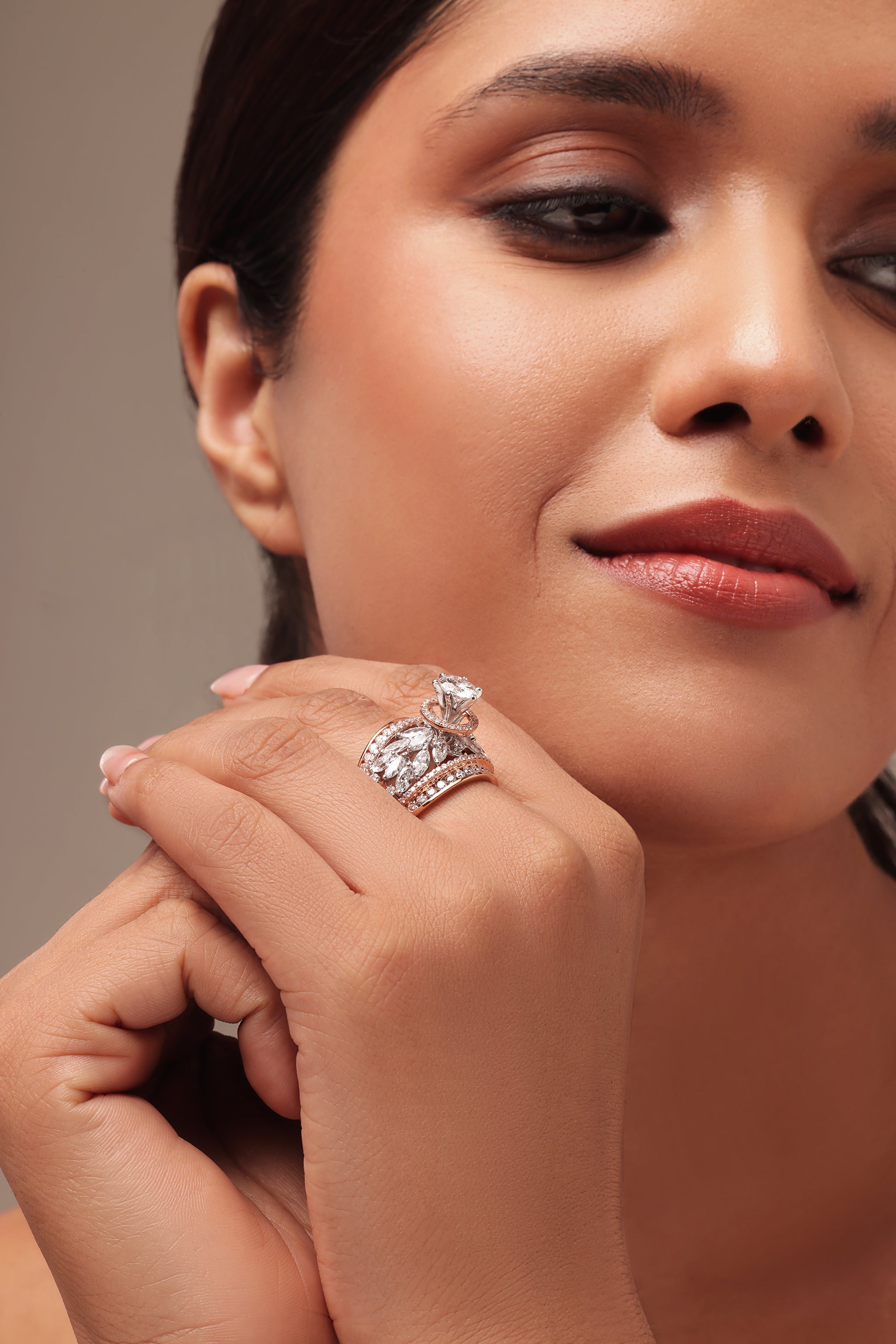 Close-up portrait of a woman modeling a dazzling cocktail ring with lab grown diamond in it. The intricate design features a prominent round solitaire with halo as the center, surrounded by elegant pear and marquise shaped diamonds on the sides.