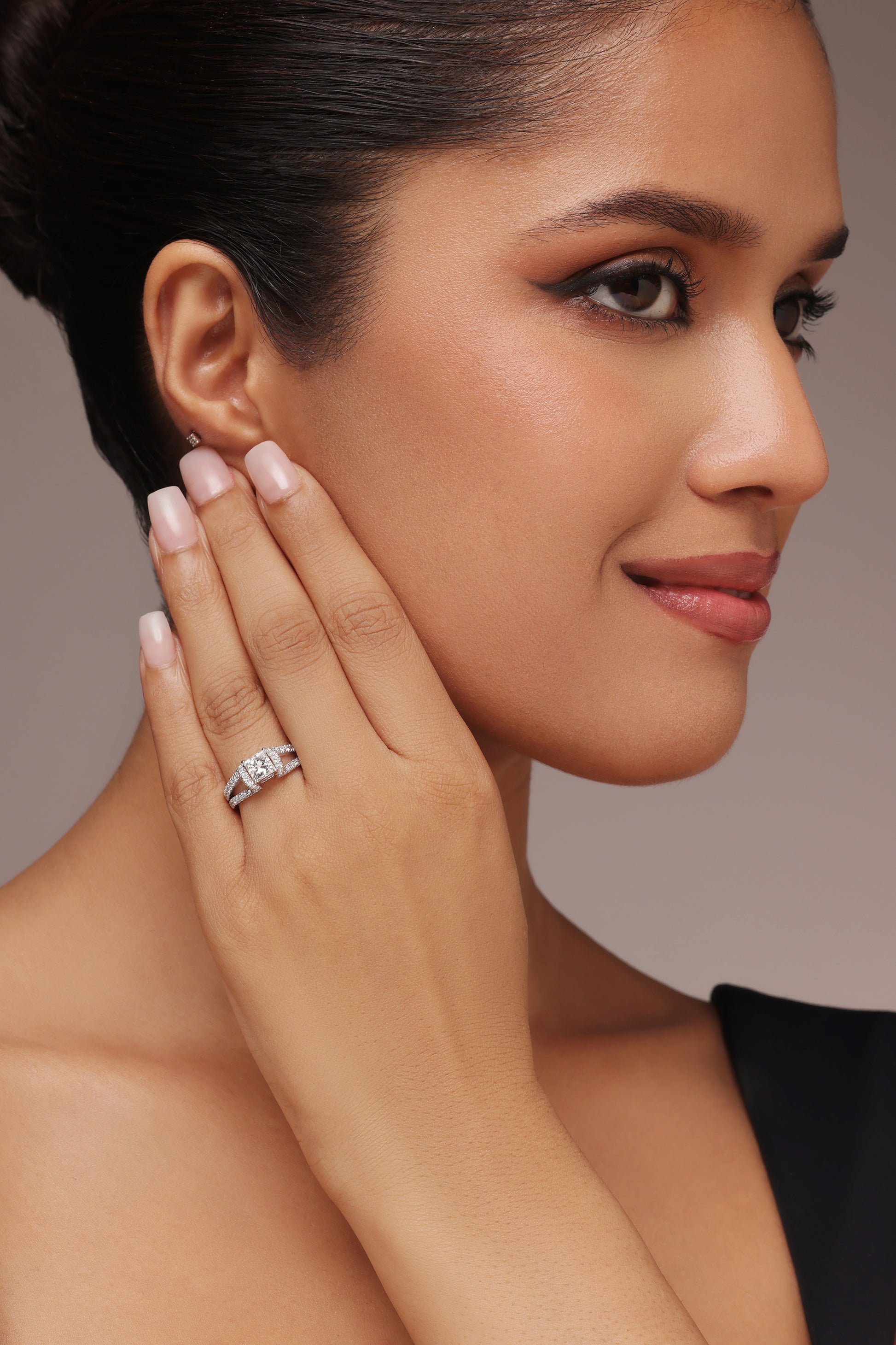 Close-up shot of a hand modeling a ring with a cushion or square-cut center stone and lab grown diamond in it, set in a modern split, pave-set open shank.