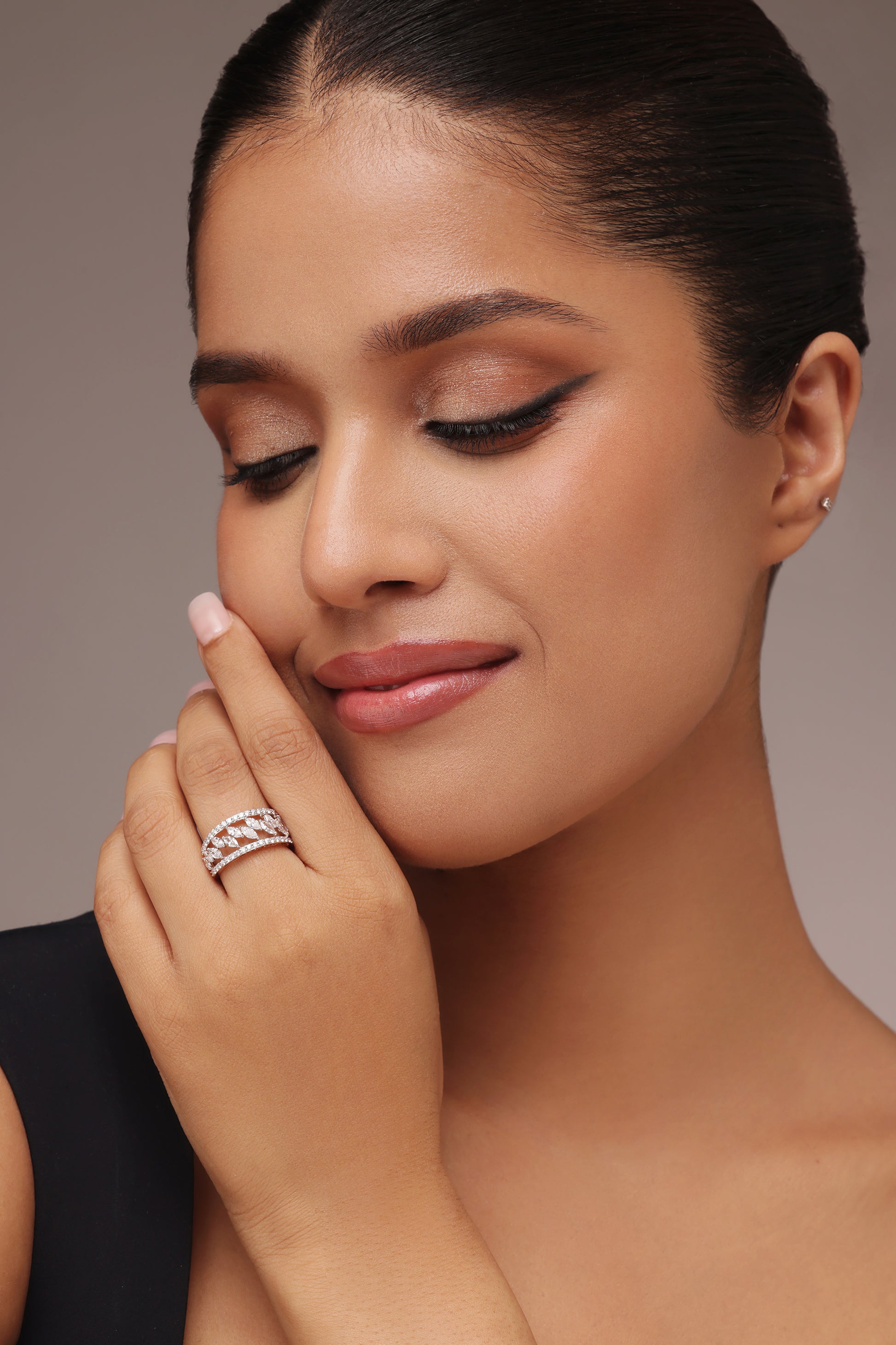 Close-up shot of a hand modeling a wide female ring with lab grown diamond in it, featuring a layered design of pavé-set round diamond borders and a central row of marquise diamonds.