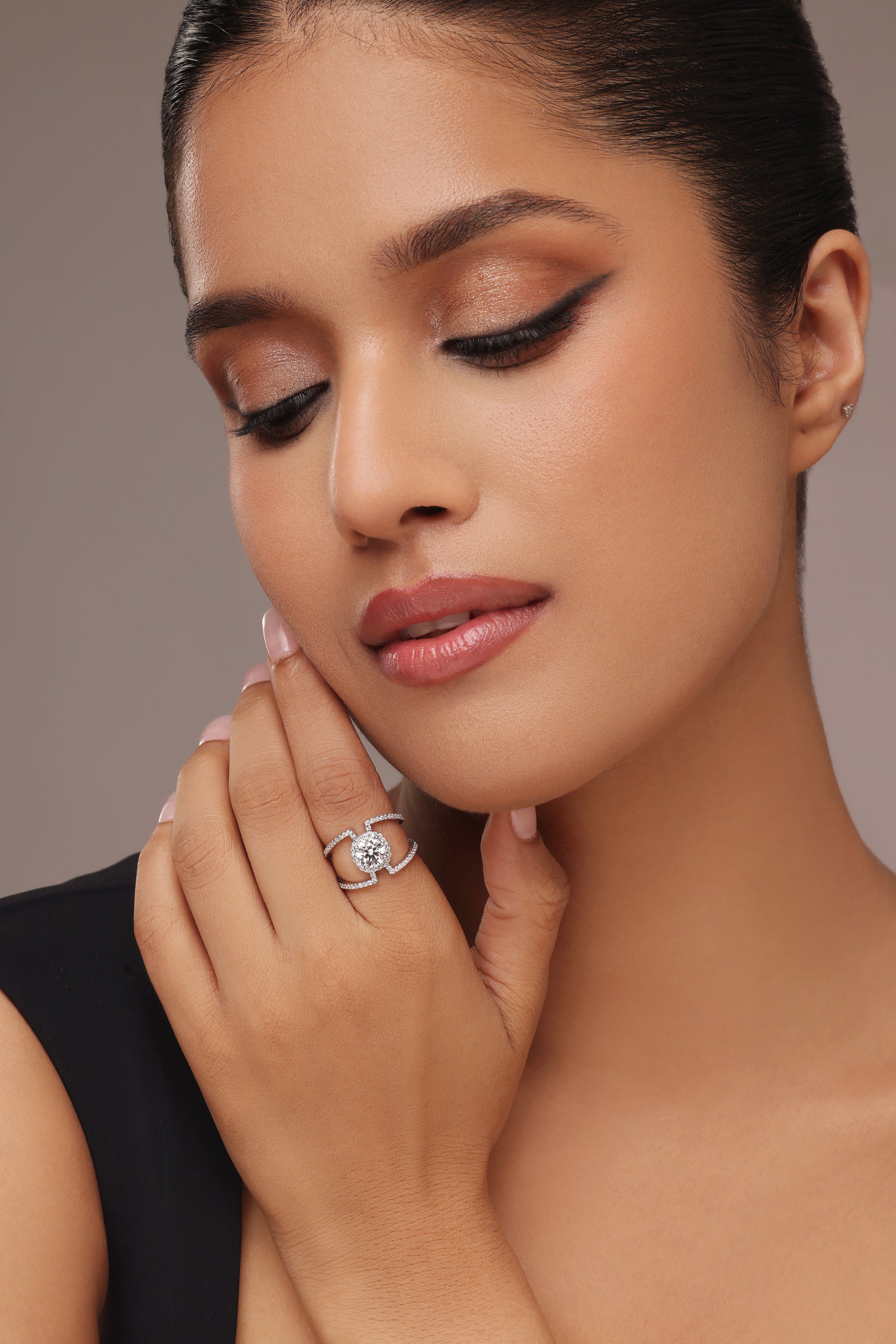 Close-up shot of a hand modeling a unique ring with a round diamond center stone and lab grown diamond in it, set in a modern open shank setting with split, pave-set bands.
