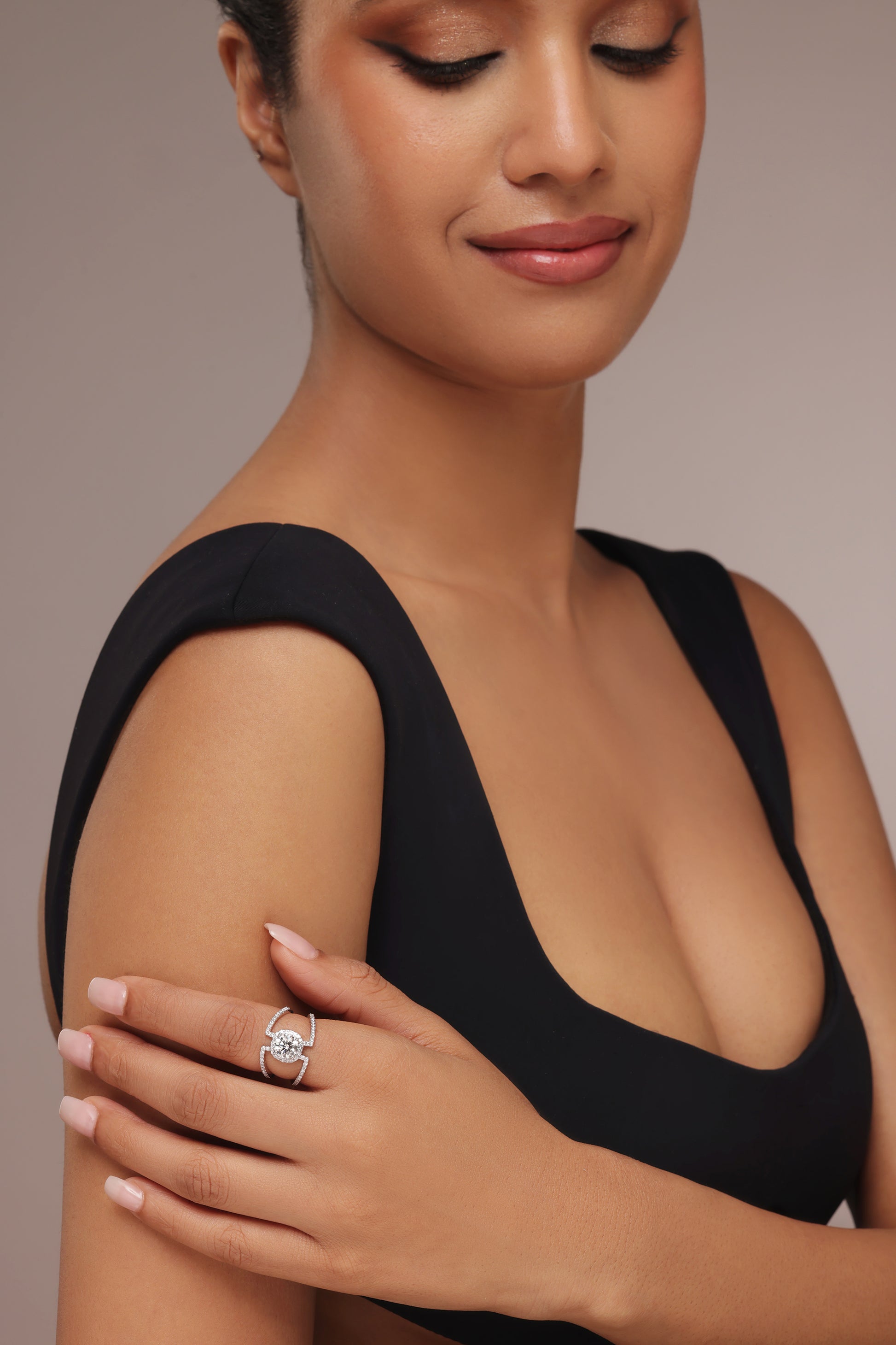Close-up shot of a hand modeling a unique ring with a round diamond center stone and lab grown diamond in it, set in a modern open shank setting with split, pave-set bands.
