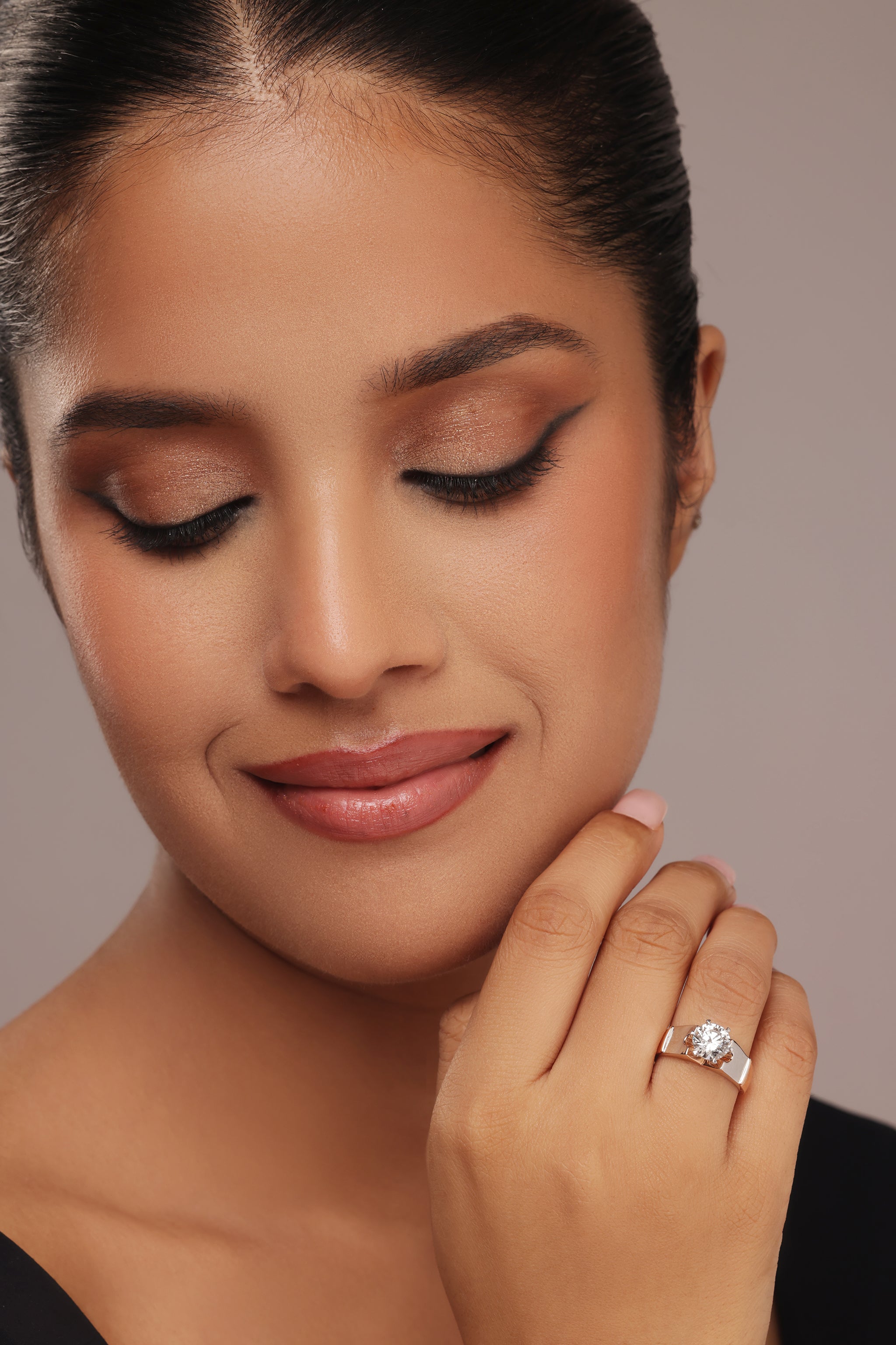 Close-up shot of a hand modeling a female ring with a prominent round lab grown diamond solitaire, set in a modern, wide, two-tone rose gold and silver band.