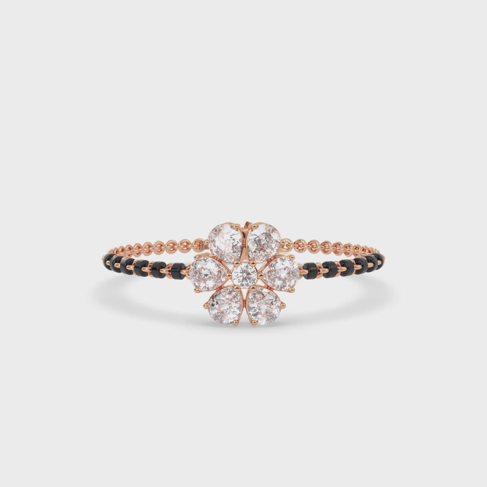 Load video: Rose gold tanmaniya bracelet featuring a floral cluster at the center composed of five pear diamond shapes and a central round stone, with the band accented by black beads and lab grown diamond in it.