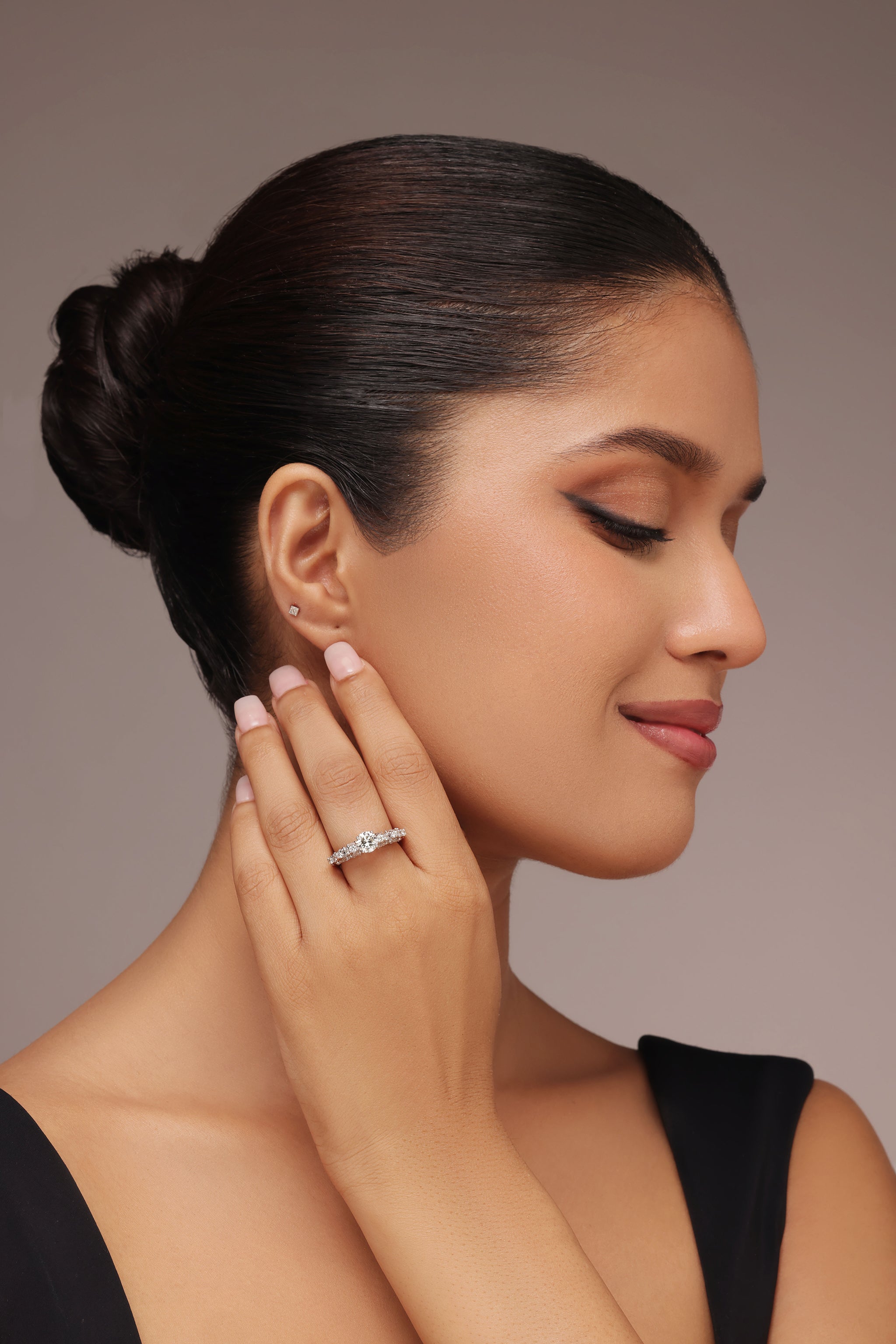 Close-up shot of a hand modeling a spectacular ring with a round diamond center stone and lab grown diamond in it. The design features a pavé round diamond on the band and large, scalloped accents on the sides resembling pear diamond shapes.