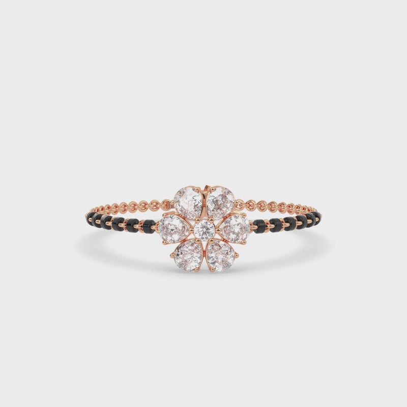 Rose gold tanmaniya bracelet featuring a floral cluster at the center composed of five pear diamond shapes and a central round stone, with the band accented by black beads and lab grown diamond in it.